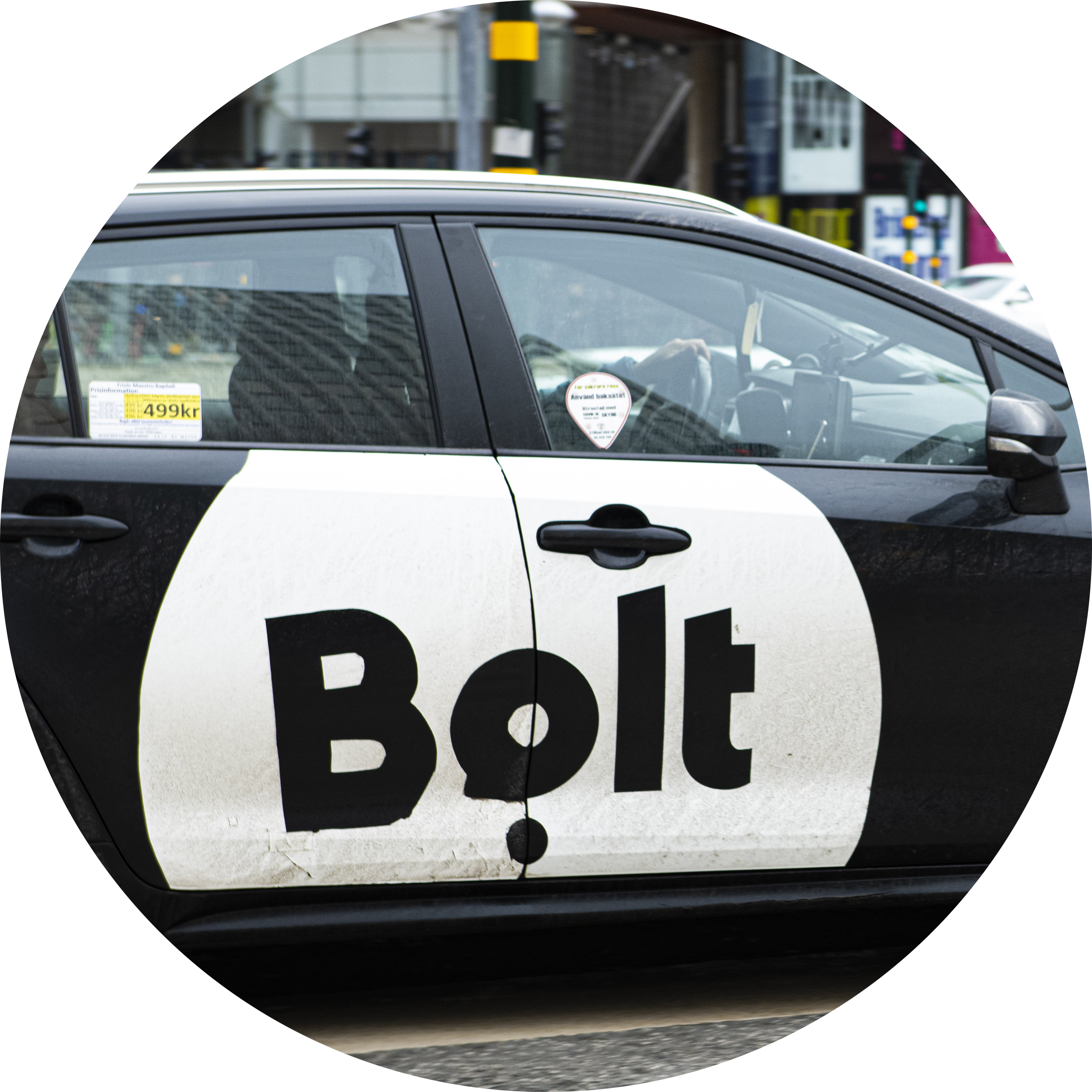 En svart bil med en stor Bolt-logotyp på sidan står parkerad på en stadsgata.