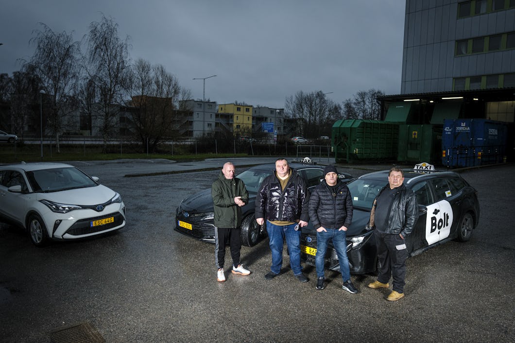 Suad Alomerovic, Enis Adrovic, Muljhan Husovic och Peter Johansson står framför två parkerade bilar, en av dem med Bolt taxiskylt, på en parkering i stadsmiljö.