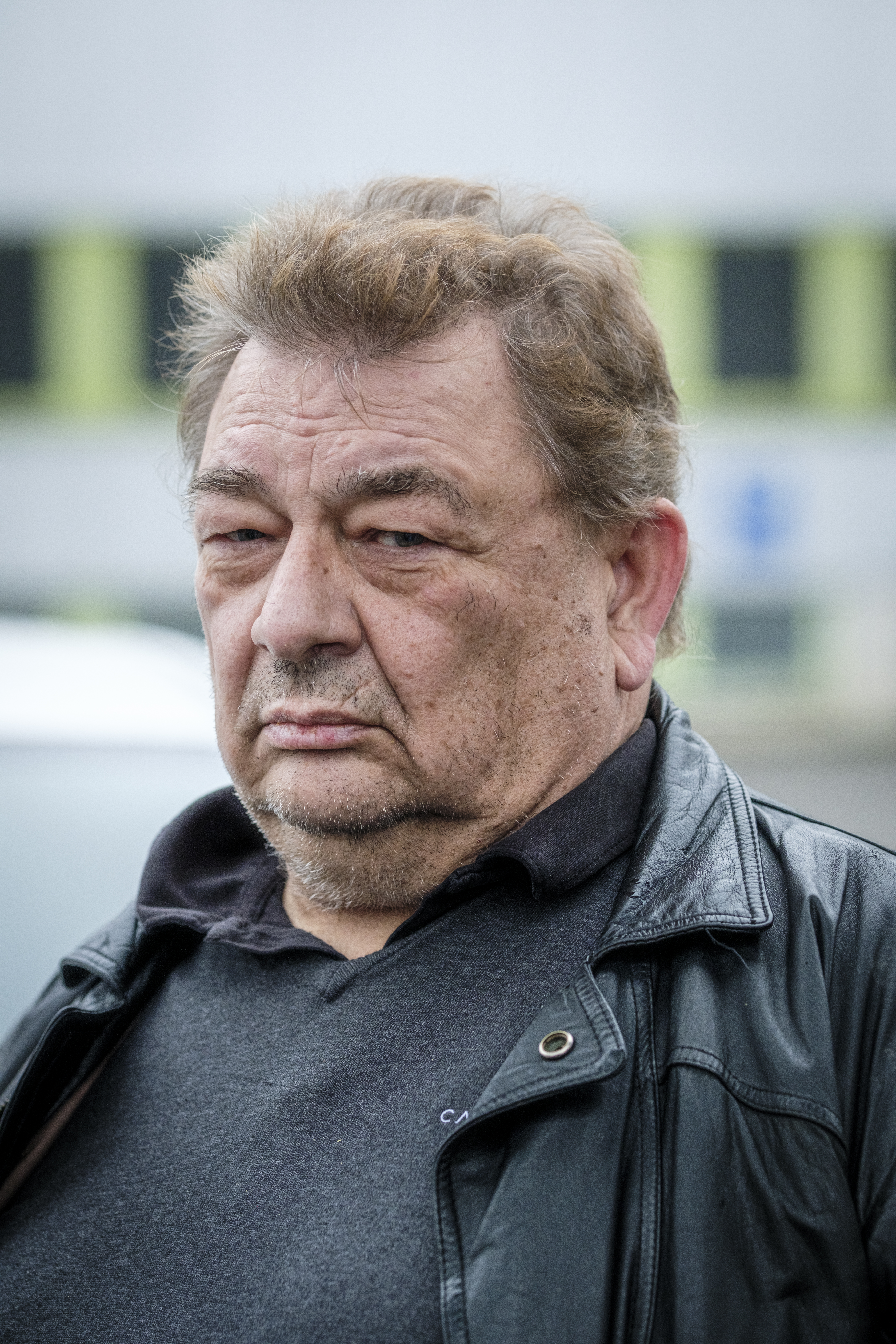 Peter Johansson med kort brunt hår och skägg har en svart läderjacka och grå tröja. Han står utomhus med neutral min.