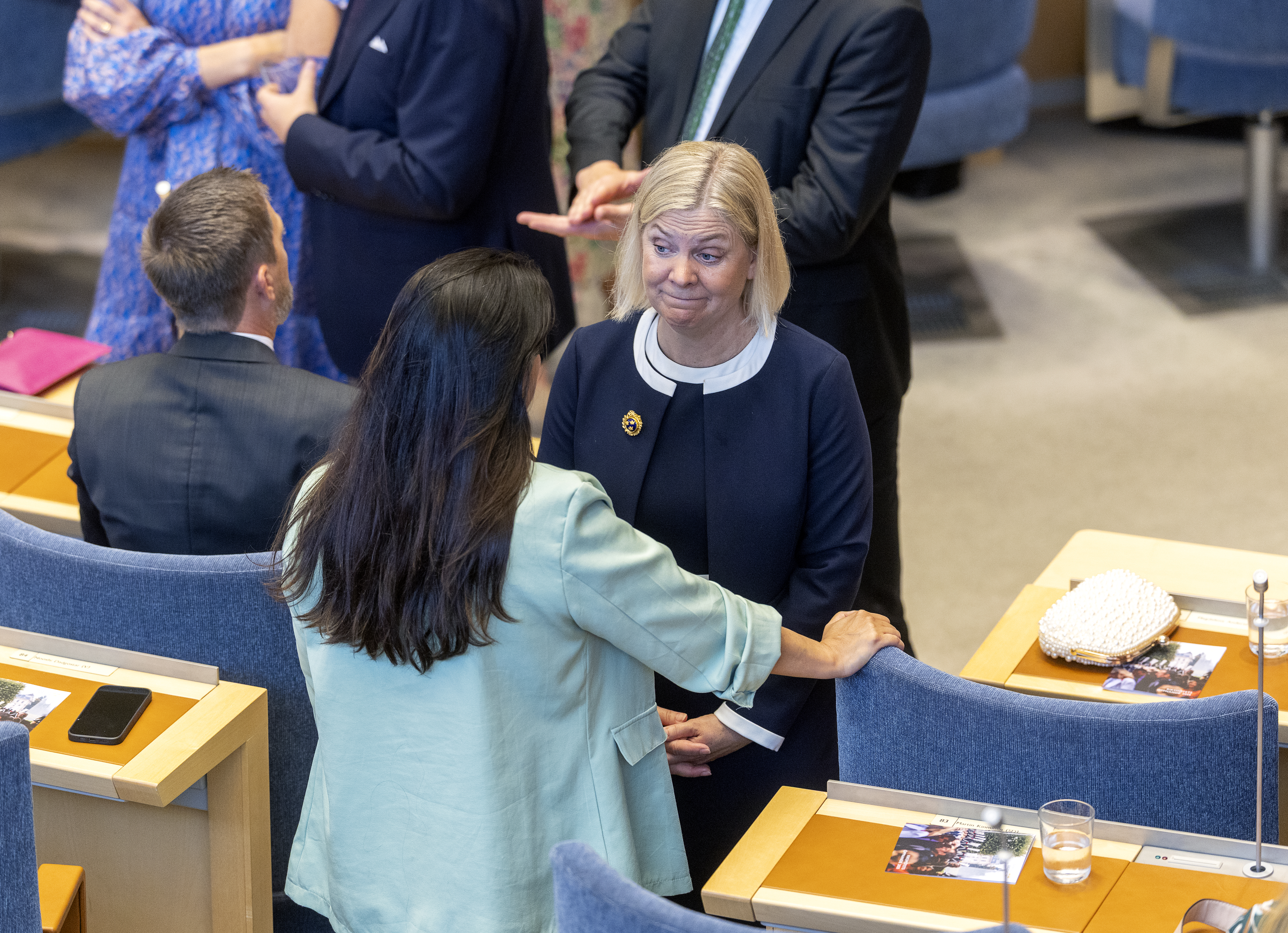 Nooshi Dadgostar och Magdalena Andersson pratar i Riksdagen, andra personer sitter eller står i närheten.