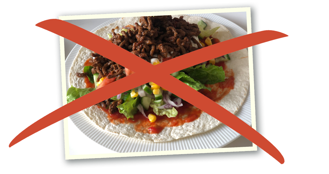 En tortillawrap med köttfärs, sallad, tomat, majs och lök på en tallrik med ett rött kors på.