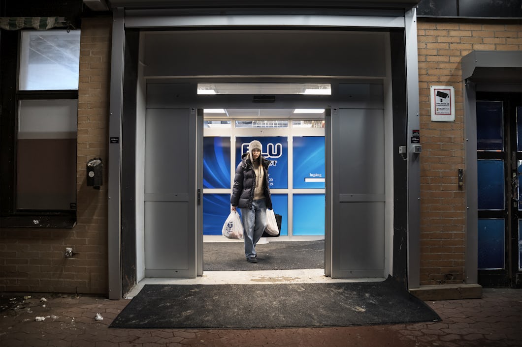 Lana håller i en plastpåse och lämnar butiken genom en automatisk skjutdörr. Det är mörkt ute.