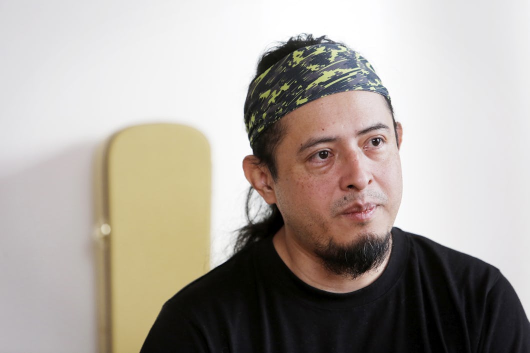 Jonathan, med skägg och mustasch, iklädd mönstrat pannband och svart tröja, sitter inomhus mot en ljus bakgrund.