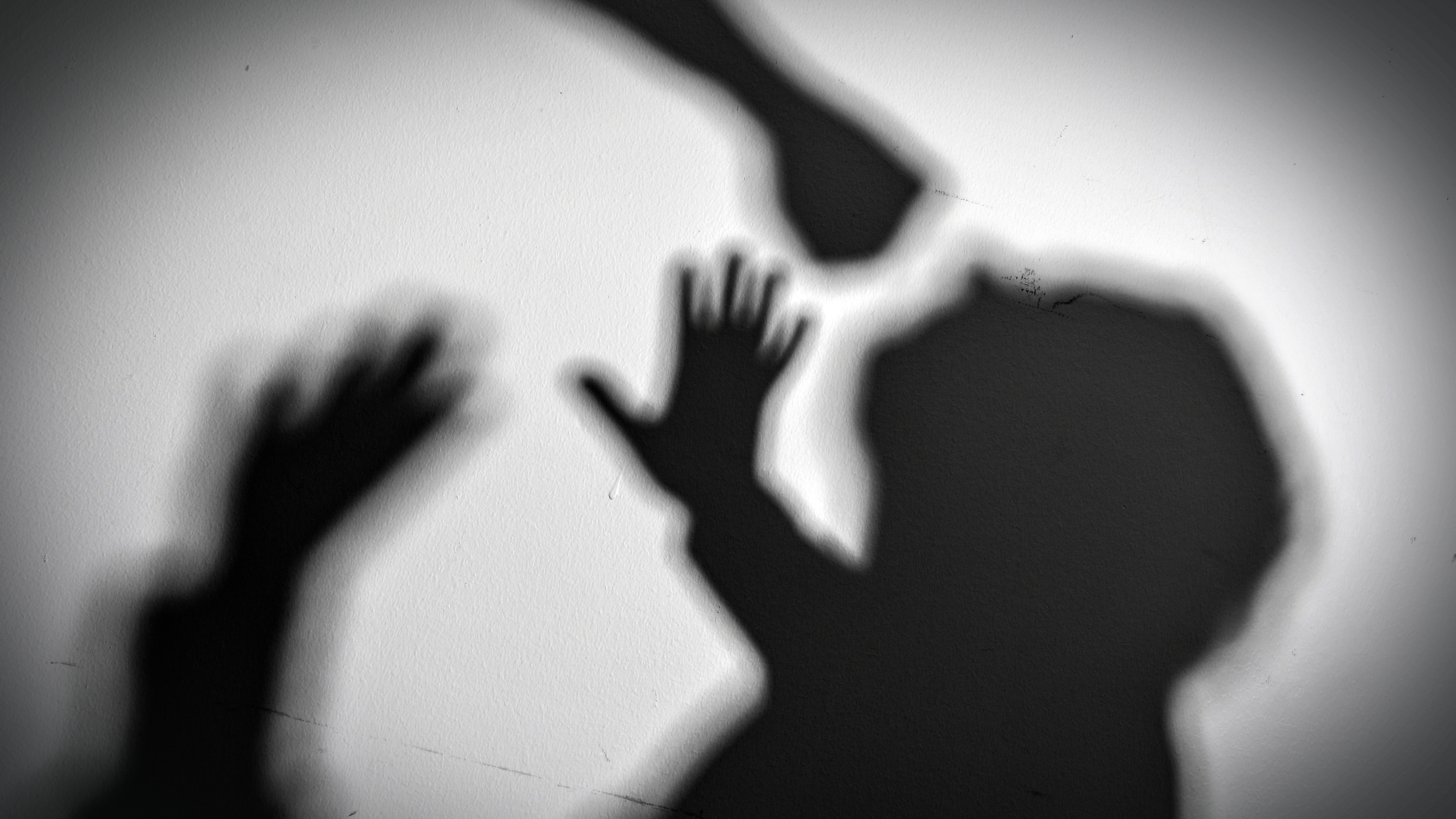 Skugga av en upphöjd knytnäve och två händer i försvarsposition, samt konturen av ett barns huvud, som indikerar konflikt.