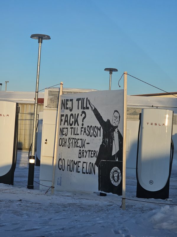Protestskylt vid Tesla-laddstationer med texten: "Nej till fack? Nej till fascism och strejkbryteri. Go home Elon" och en teckning av Elon Musk. Snötäckt mark.