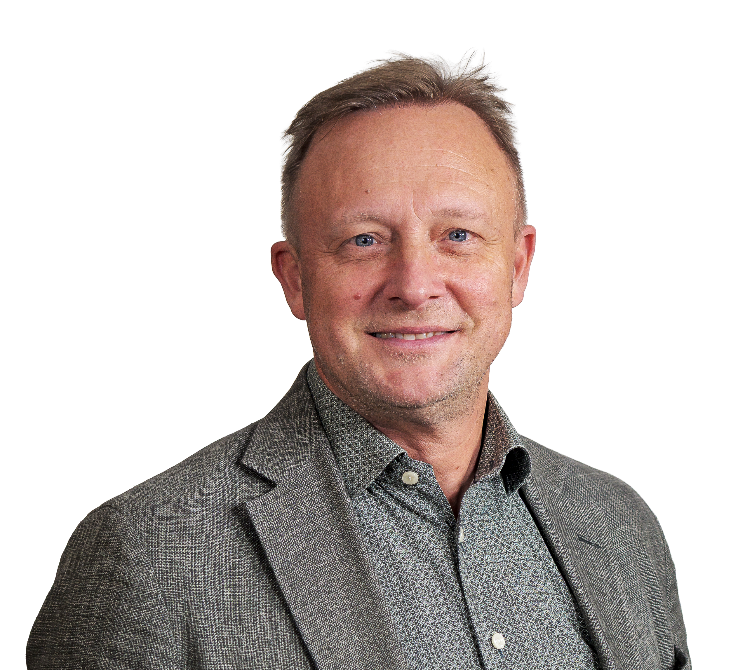 Man med grå kavaj och mönstrad skjorta som ler mot kameran framför en vit bakgrund.