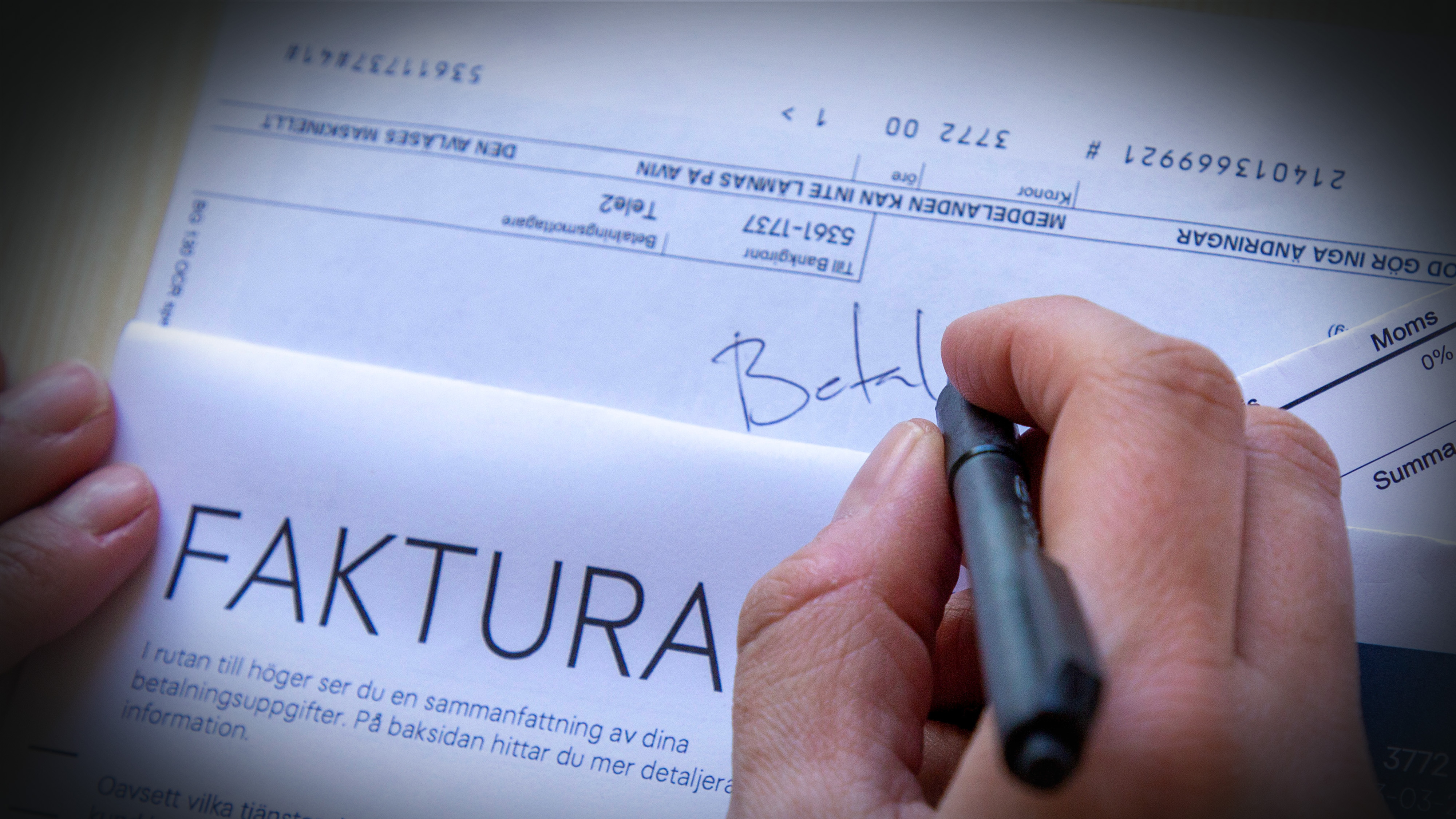 En person skriver "Betal" på ett dokument märkt "FAKTURA" och håller en penna och papper med betalningsuppgifter.