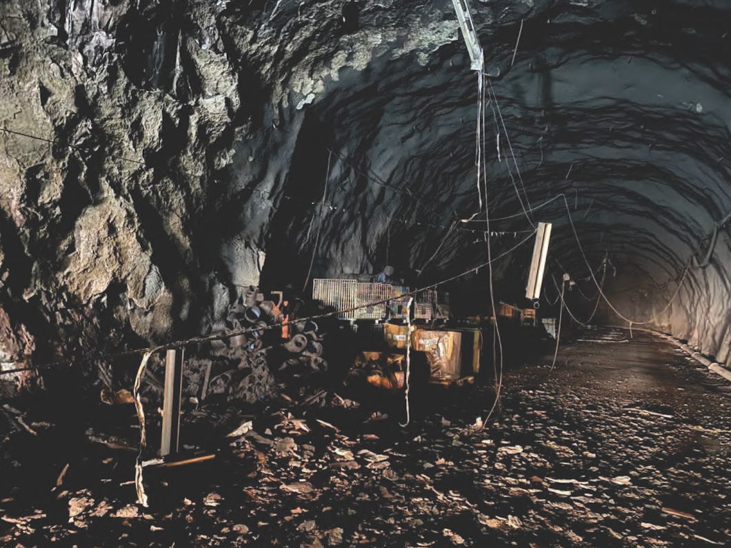 Inne i bergtunneln ligger brandskadad utrustning, skräp och kablar utströdda över ojämna golv.