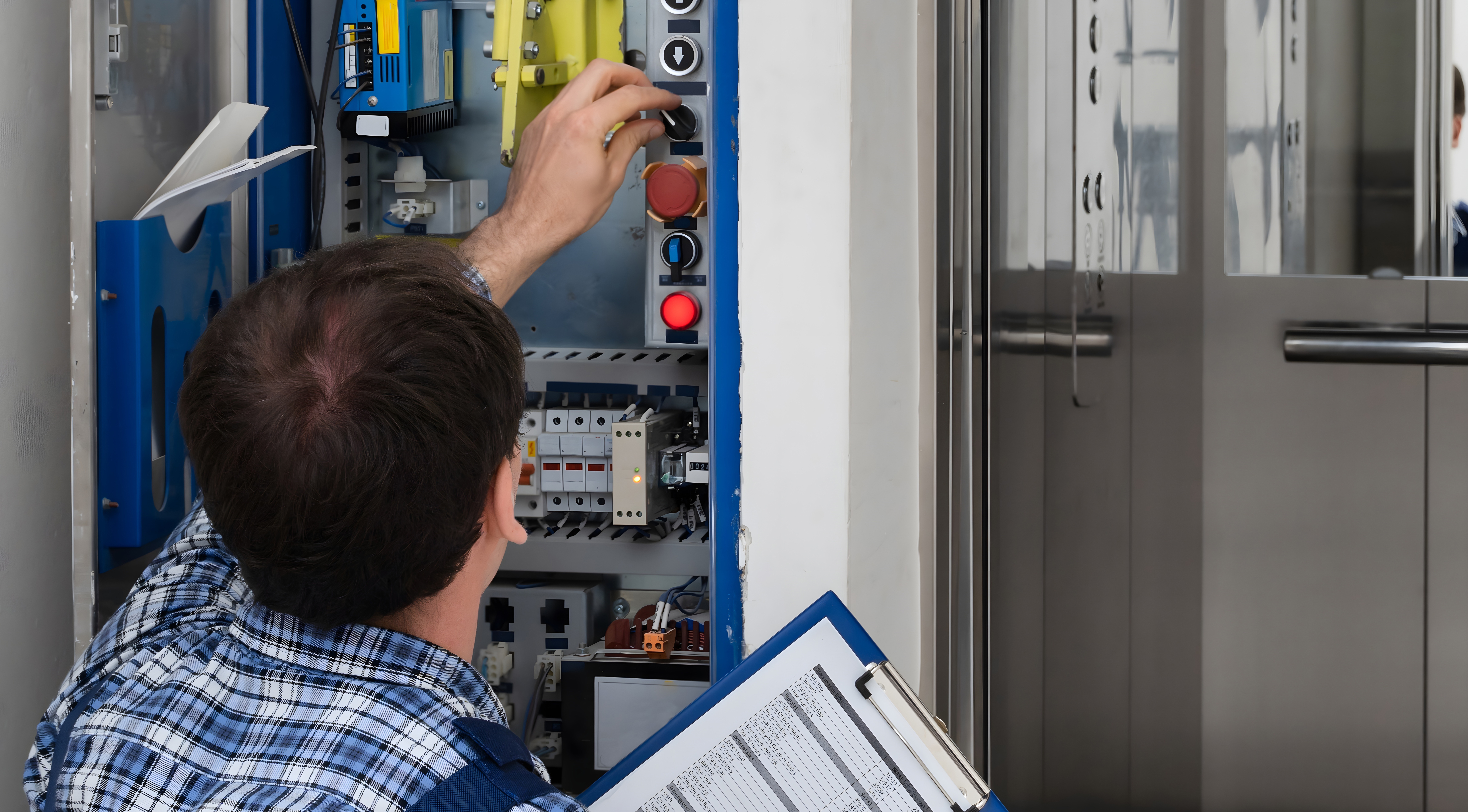 En tekniker justerar reglage i ett elskåp och håller i en pärm med dokument.
