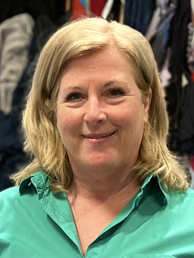 Matilda Wester, med blont hår och skjorta med grön krage, ler mot kameran med kläderna suddiga i bakgrunden.