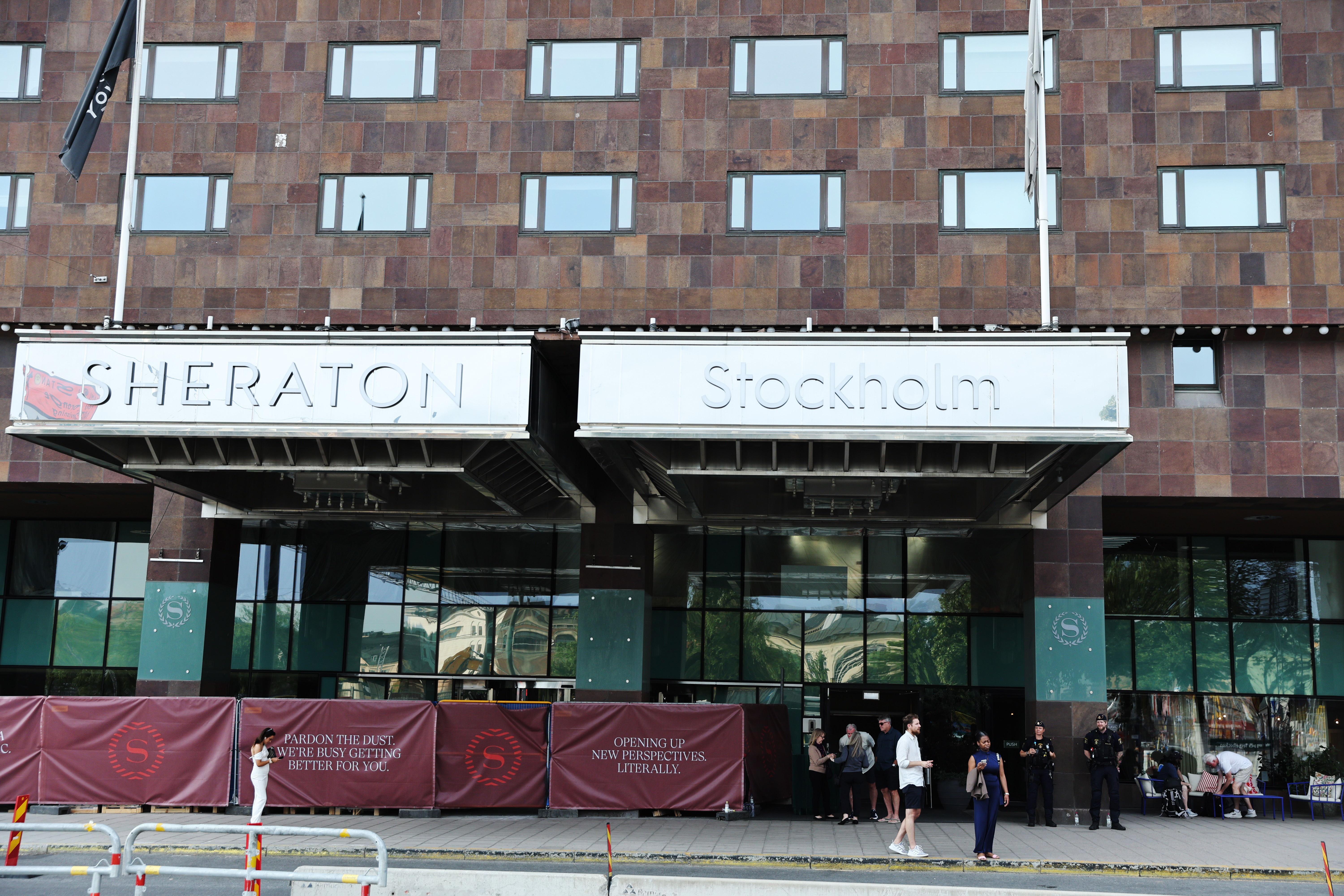 Huvudingången till Sheraton Stockholm Hotel med personer utanför och mörkröda banderoller längs trottoaren.