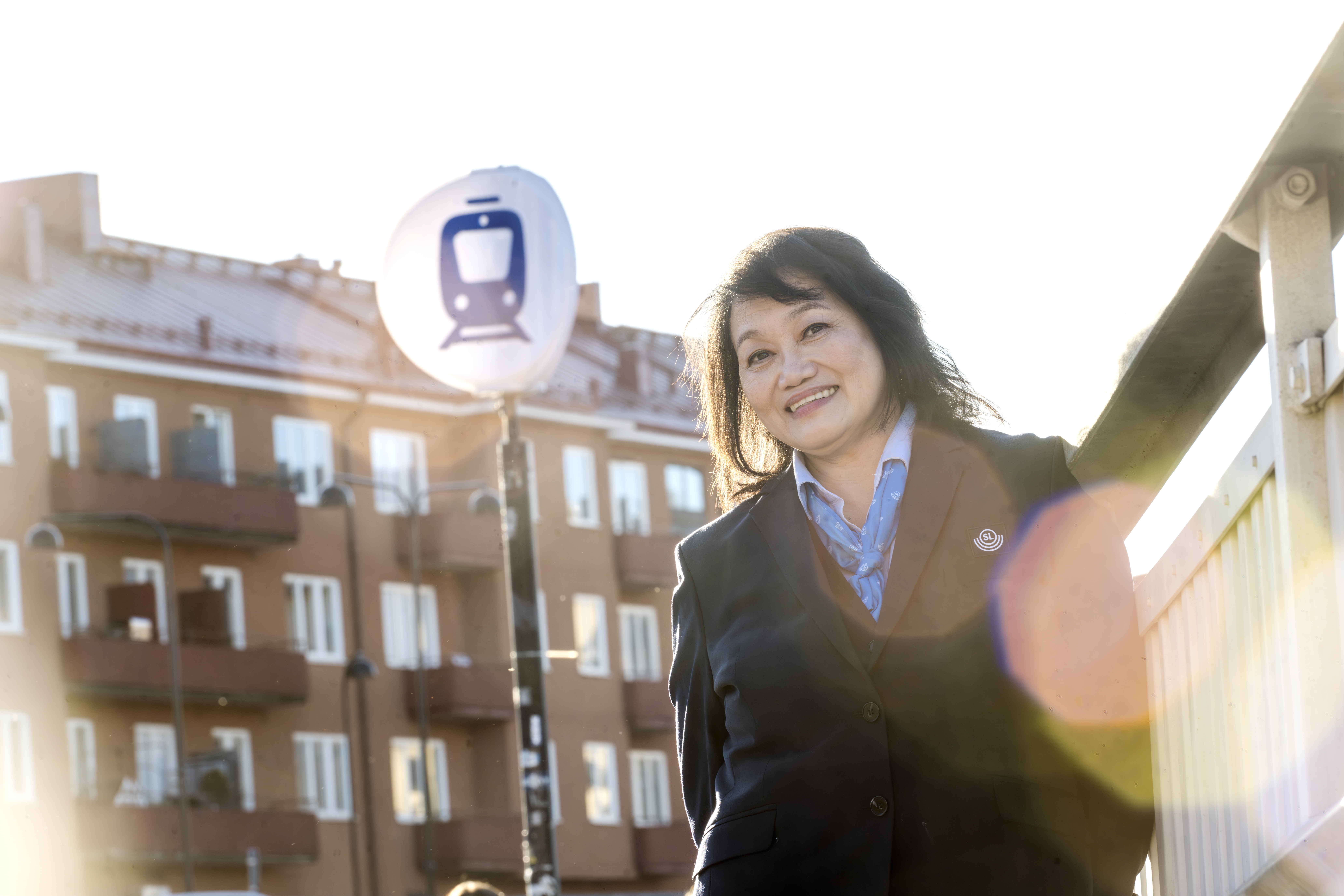 Editha Domingo framför en tågstationsskylt utomhus.