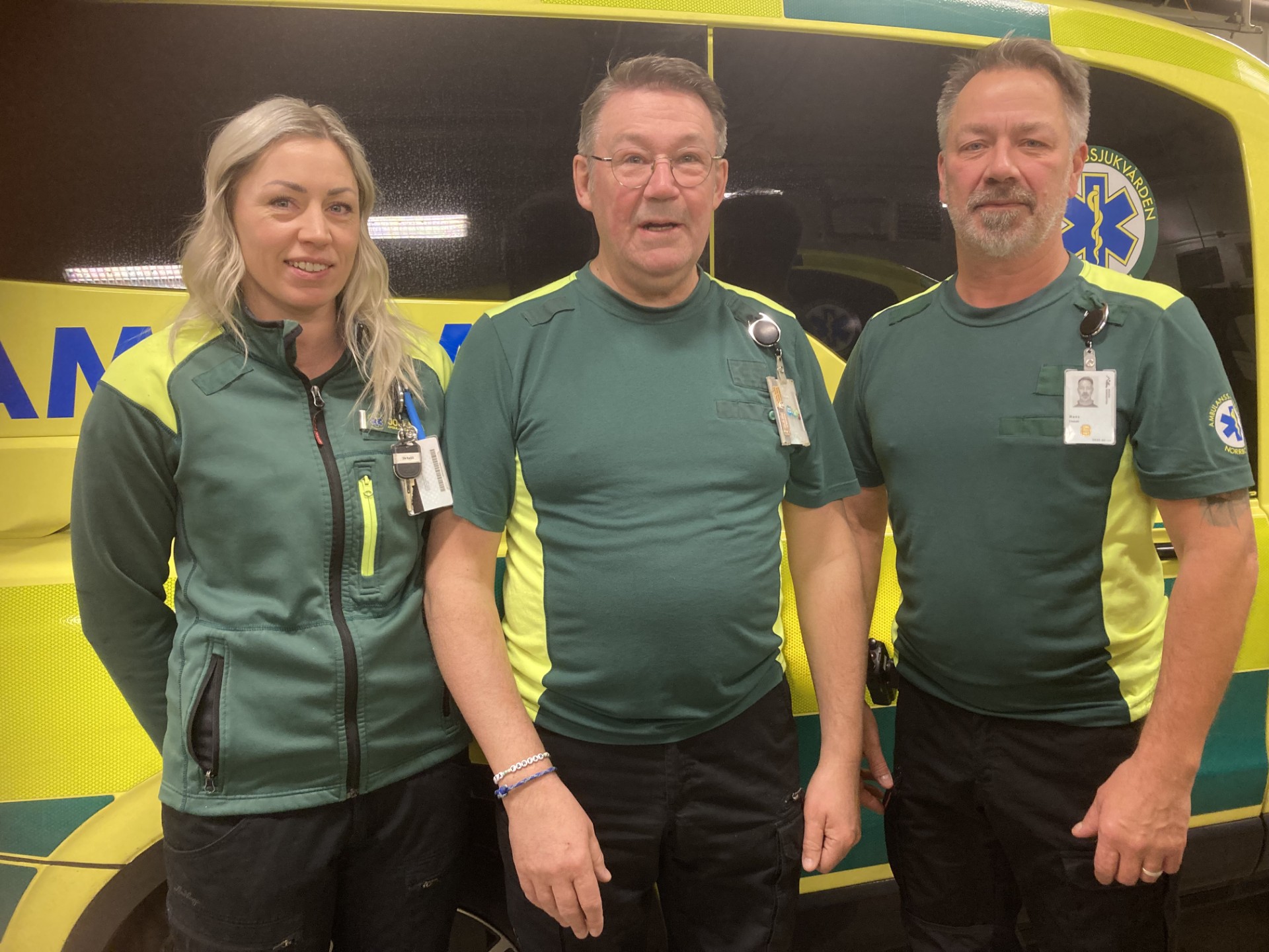 Tre ambulanspersonal framför en ambulans