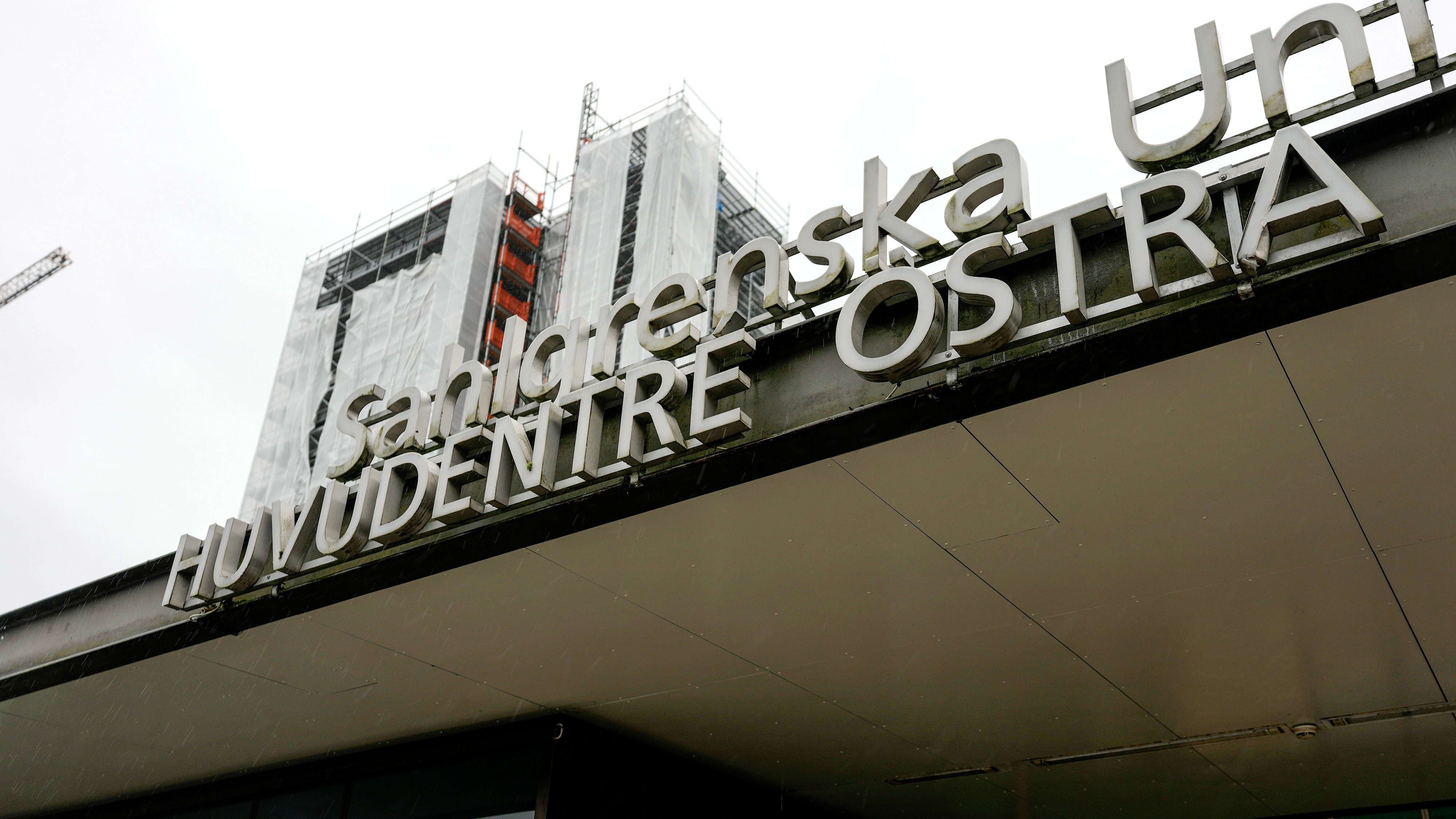 Skylt för Sahlgrenska universitetssjukhus östra entré med en delvis täckt byggnad under konstruktion i bakgrunden.