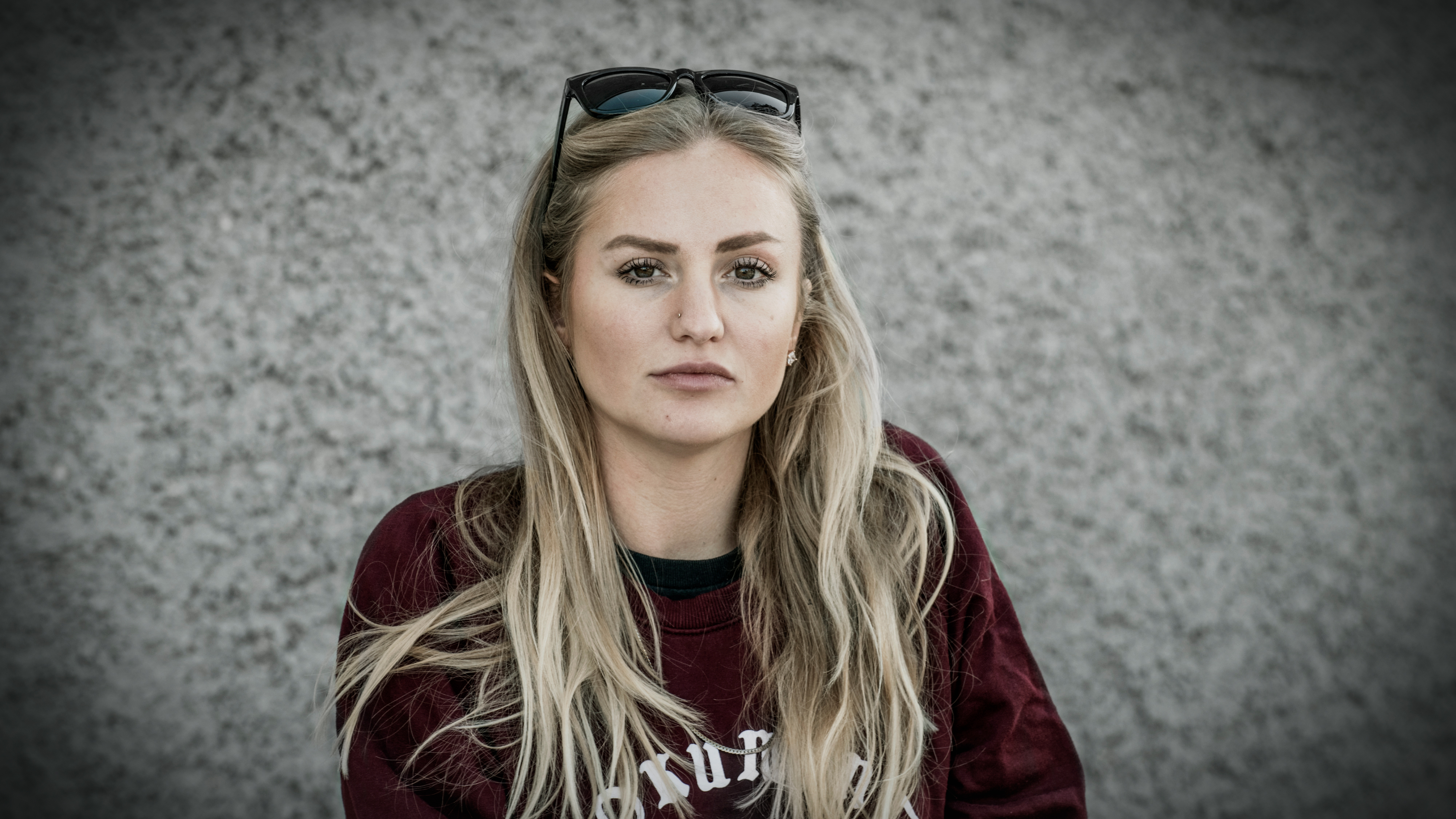 Saga Berlin med långt blont hår, i en mörkröd tröja och solglasögon på huvudet.