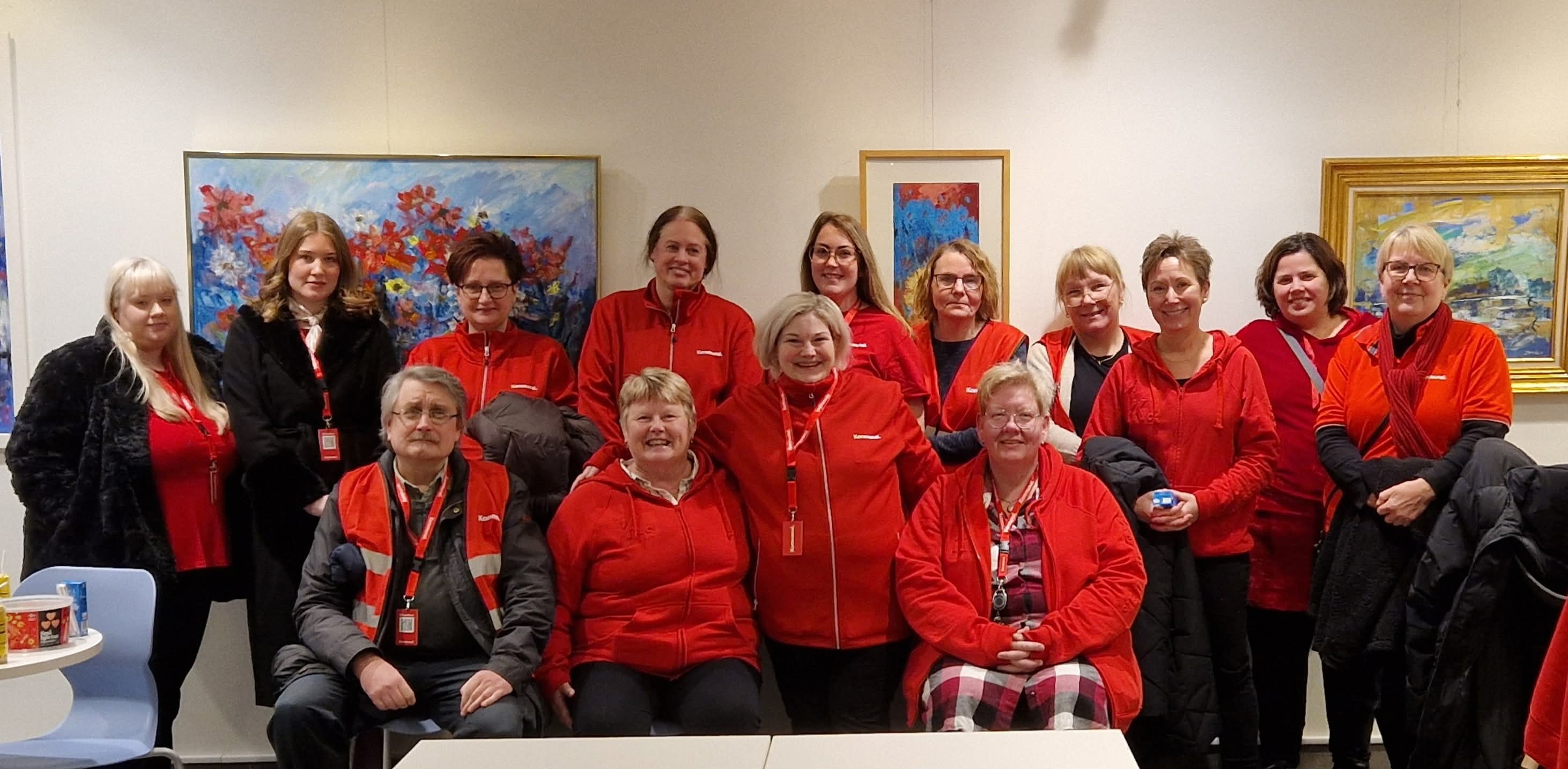 En grupp människor som bär röda gemensamma kläder inomhus.