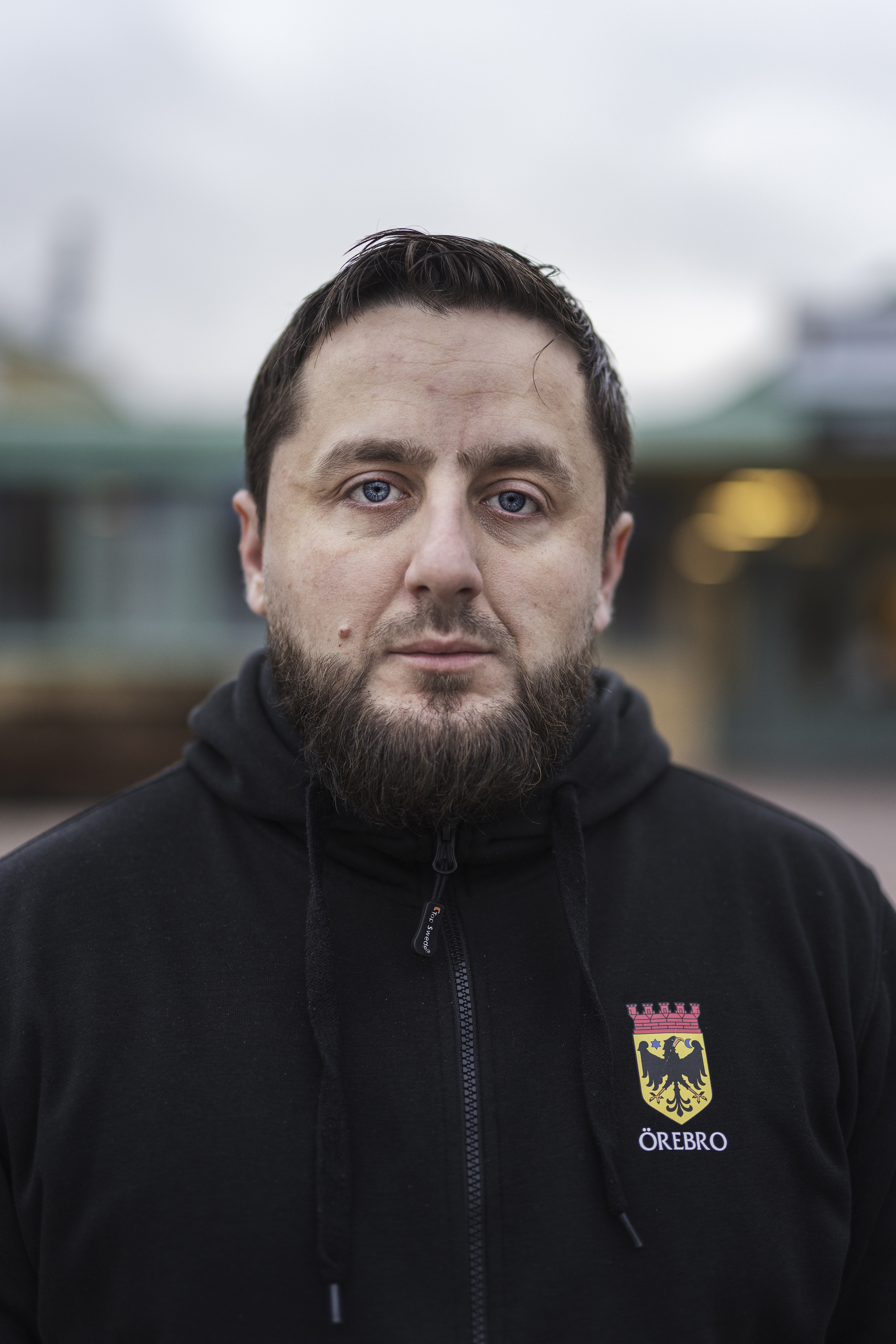 Adnan Imsirovic har på sig en svart hoodie med "Örebro"-märke. Han står utomhus och tittar mot kameran. Bakgrunden är suddig.