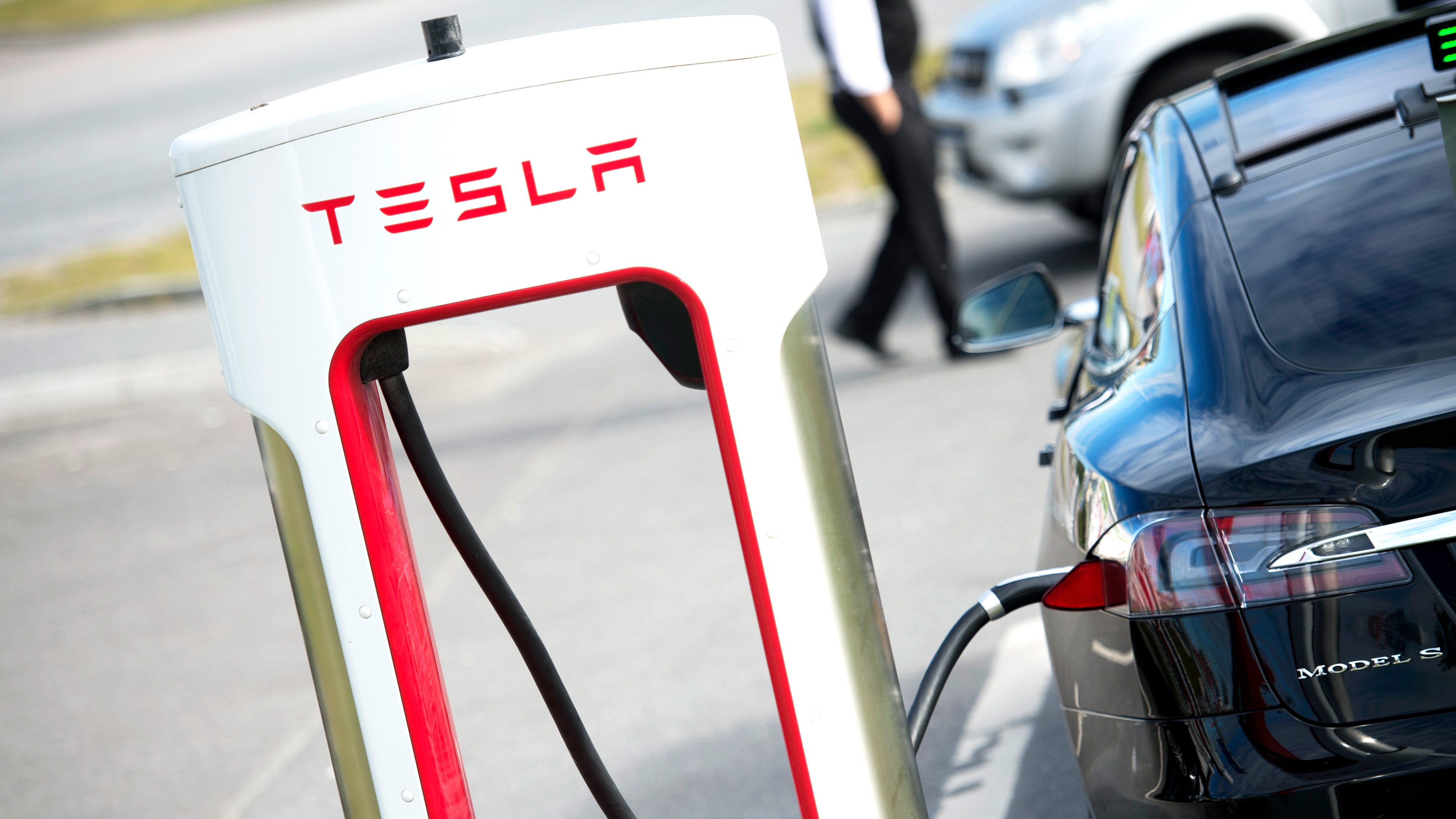 En Tesla-elbil är ansluten till en Tesla Supercharger vid en laddstation.