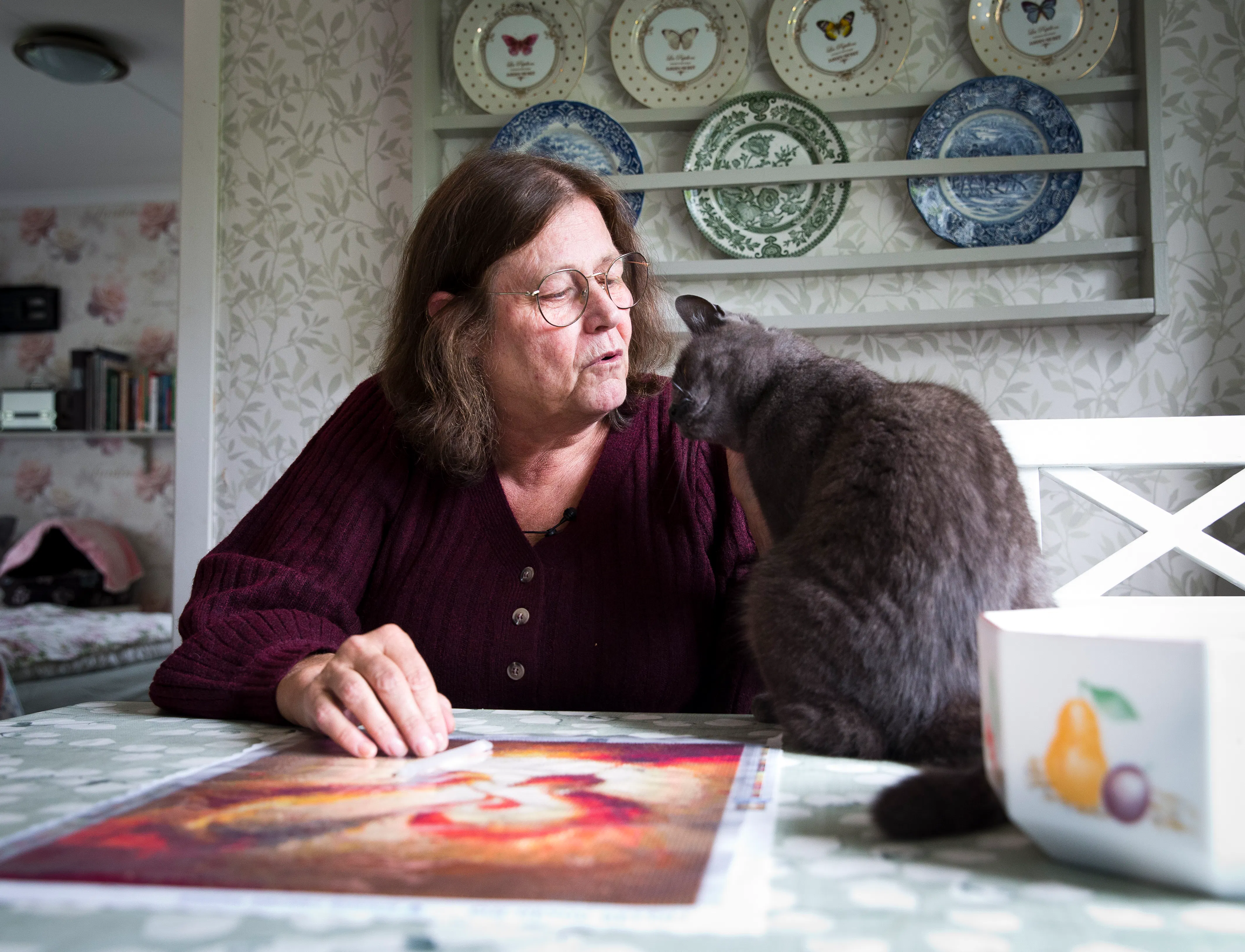 Helen Wikner sitter vid ett bord med en katt framför sig.