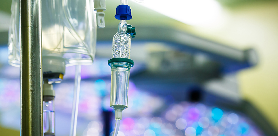 Dropp hängande på en stolpe på sjukhus, med LED-kirurgiska lampor i bakgrunden.