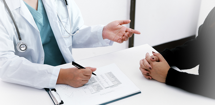 Läkare i vit rock pratar med en patient.