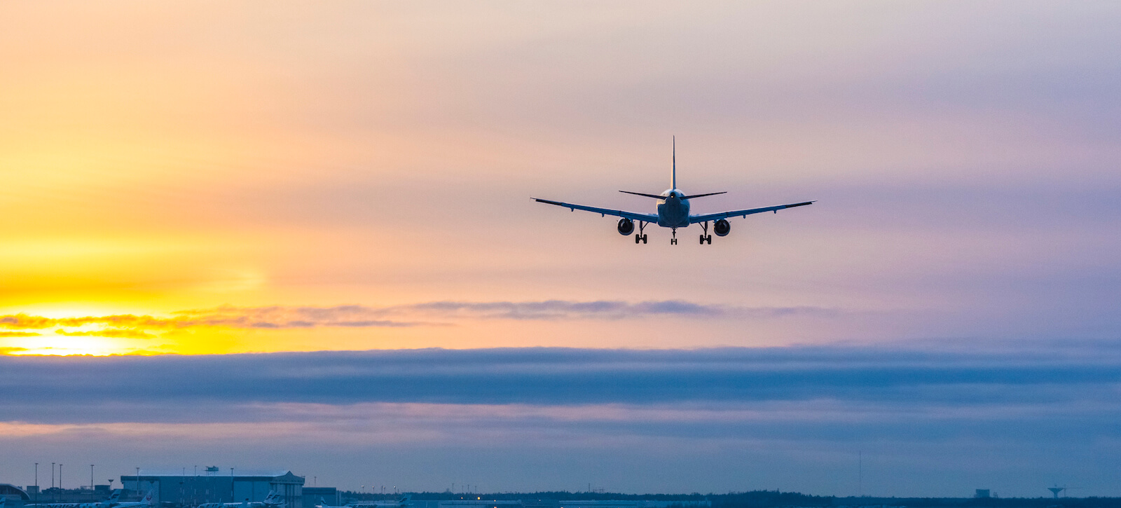 Flygplan i solnedgången på väg att landa.