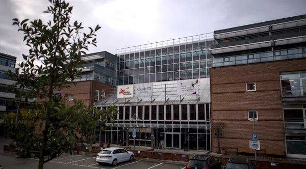 Strålsäkerhetsmyndighetens byggnad i tegel, med en parkeringsplats med ett träd framför.