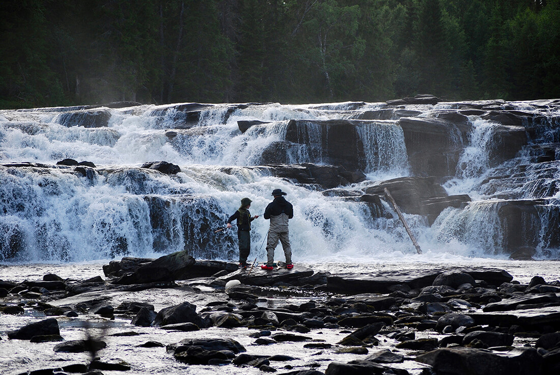 Två personer som fiskar i fors