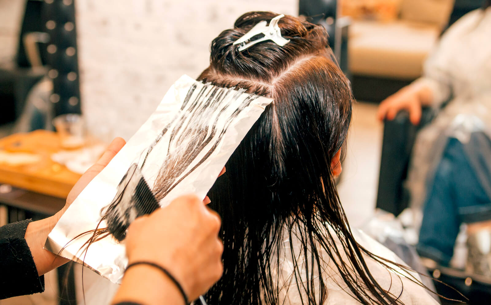 Kvinna får håret färgat på en frisersalong.