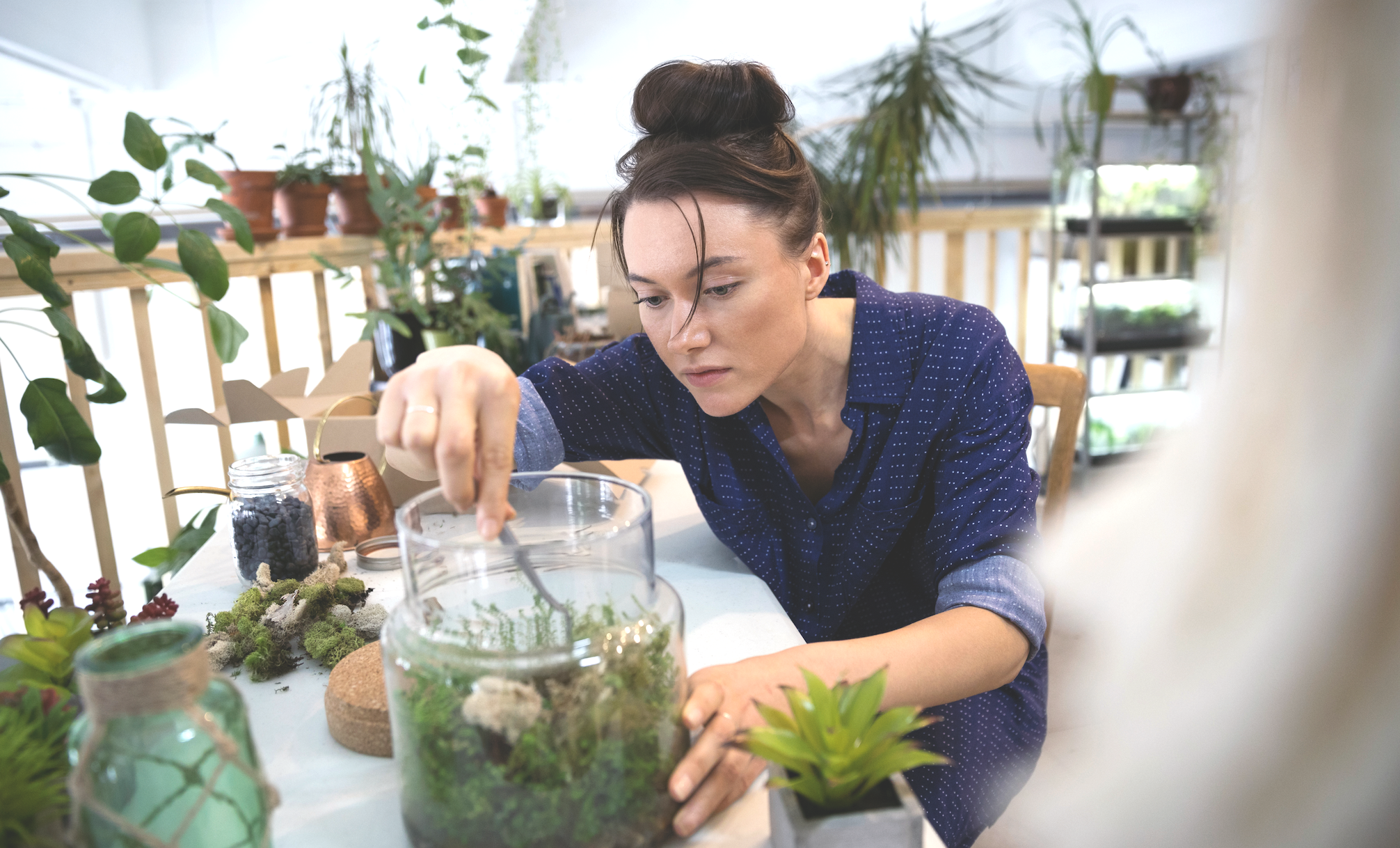 Kvinna som plockar med kvistar och stenar i en glasburk.