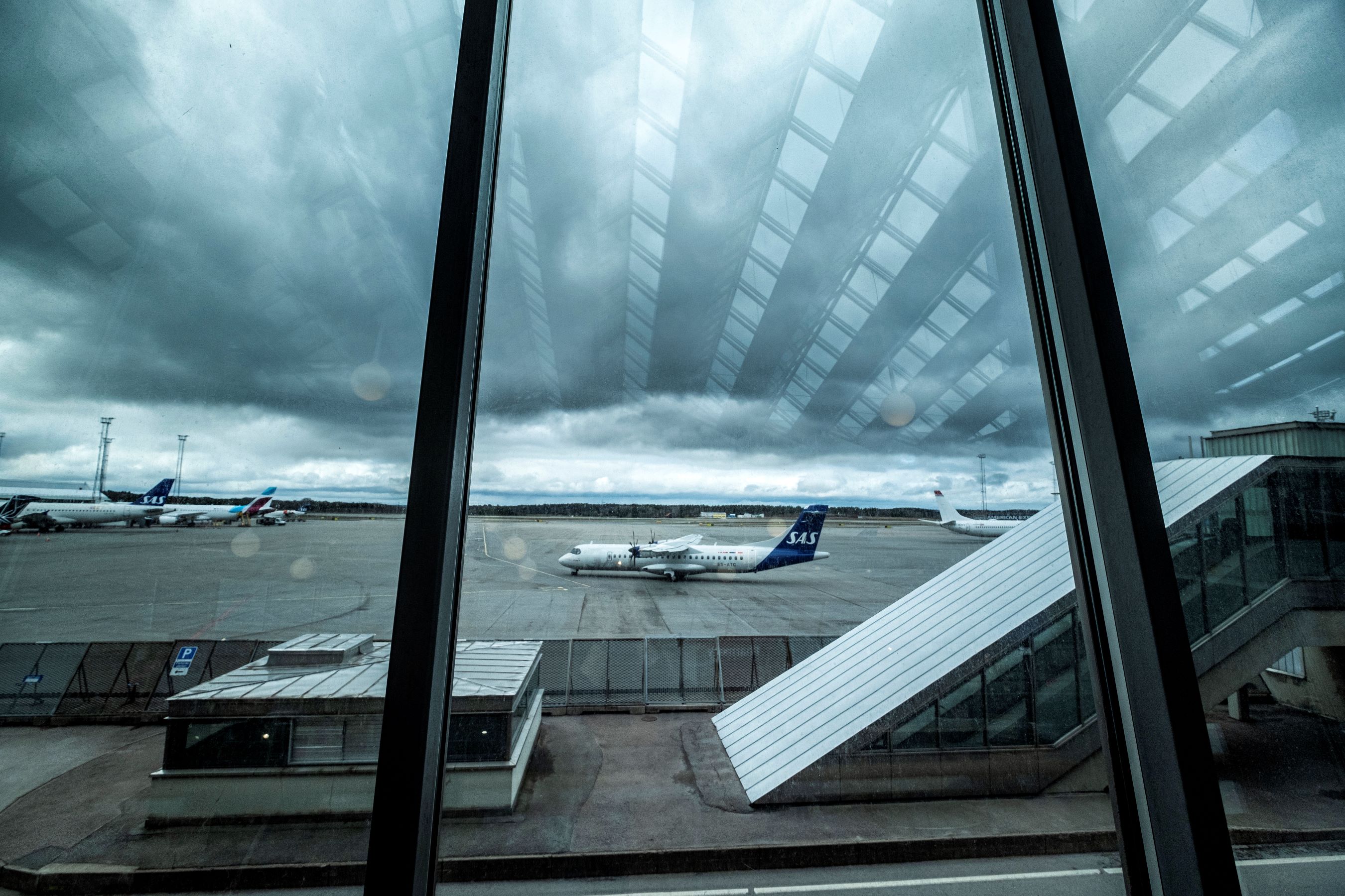 Flygplan genom fönster på flygterminal.