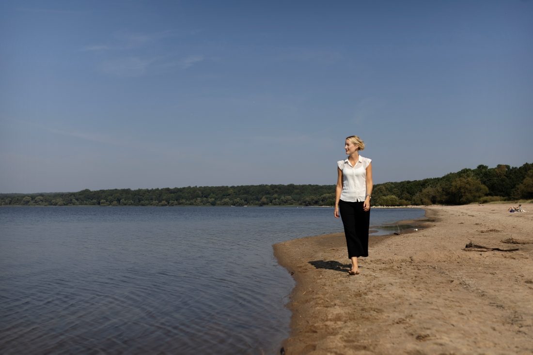 Kvinna på strand vid sjö.