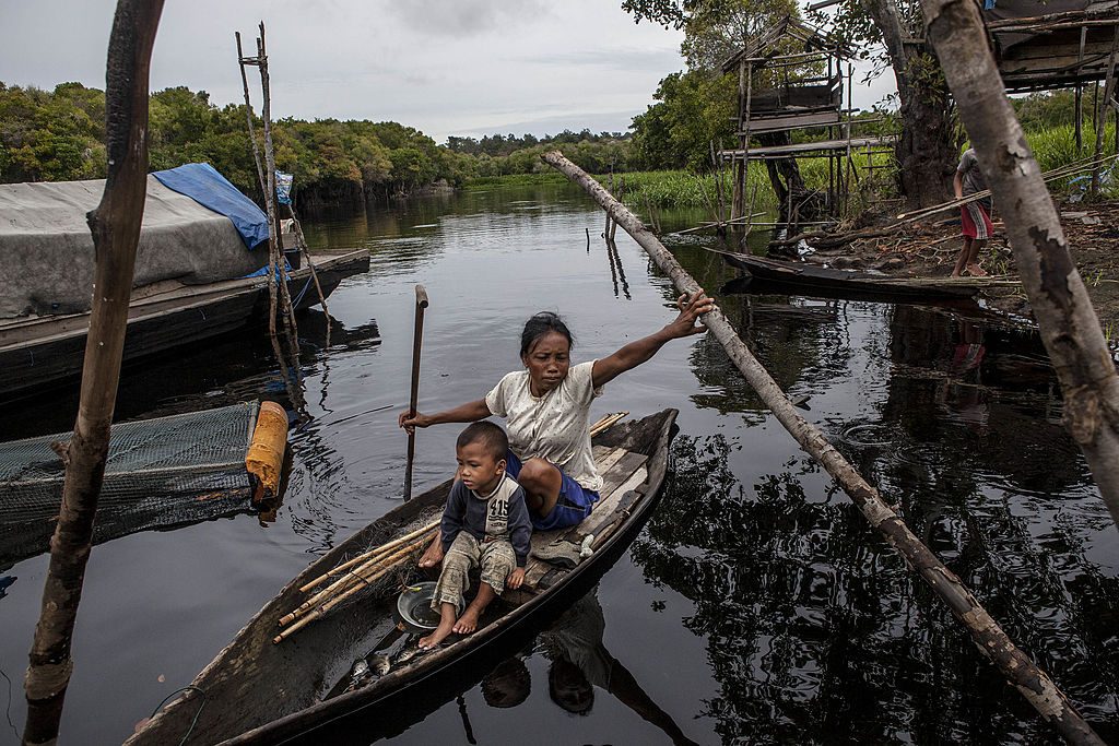 Kvinna med barn i kanot på flod