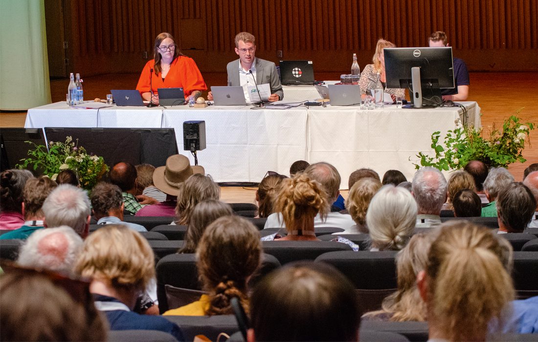 Personer vid presidium och datorer.