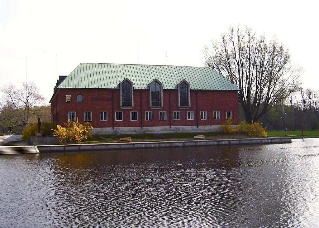 Tegelhus med koppartak, vid vatten.