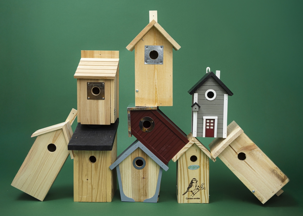 Staplade fågelholkar mot grön bakgrund.