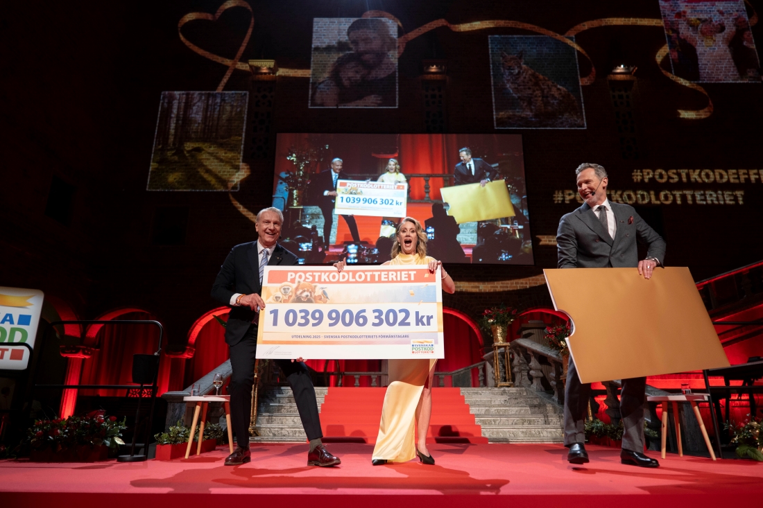 Två män och en kvinna med stor check på scen.