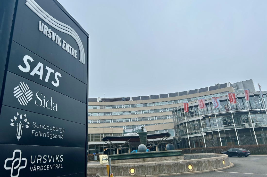 Skylt med företagsnamn framför kontorsbyggnad.