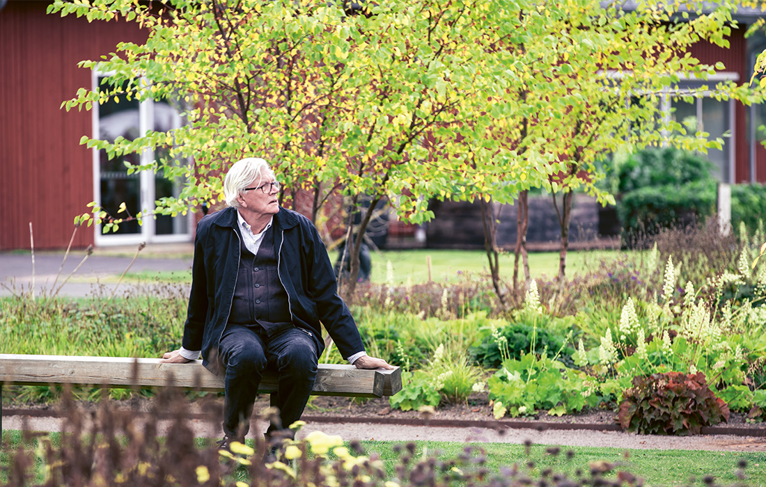 Piet Oudulf sitter på en bänk i trädgården i Vandalorum.