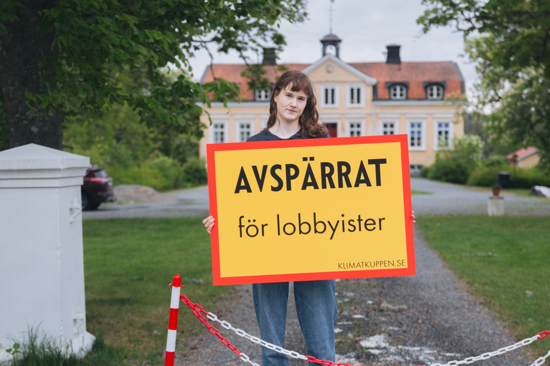 Kvinna med skylt framför hus.