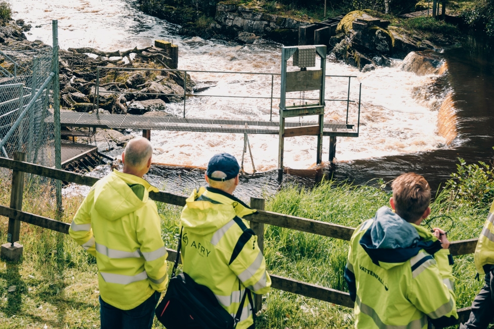 Män i gula jackor vid vattenkraftverk.
