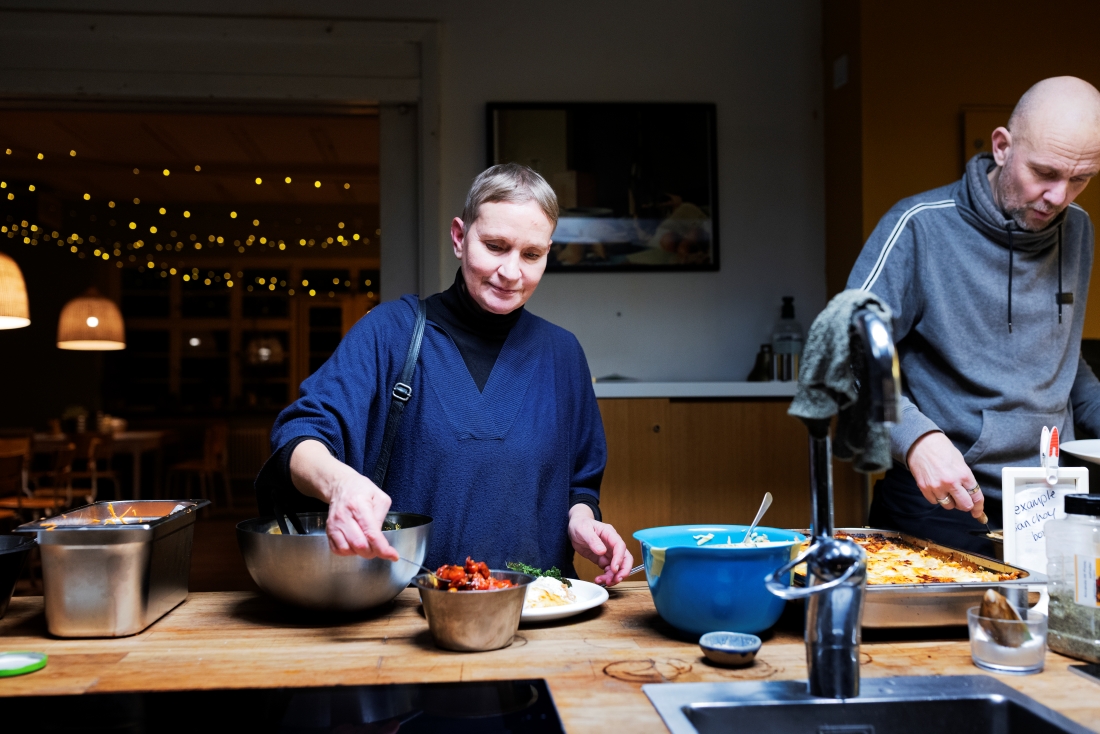 Kvinna och man tar mat i kök.