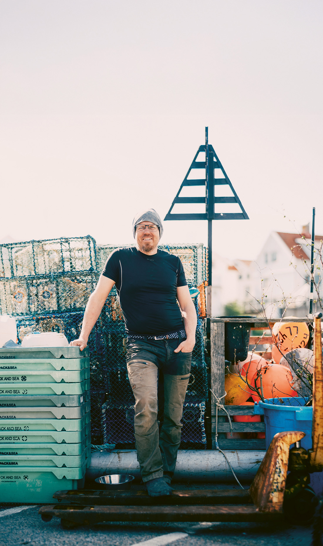 Man vid fisklådor i hamn