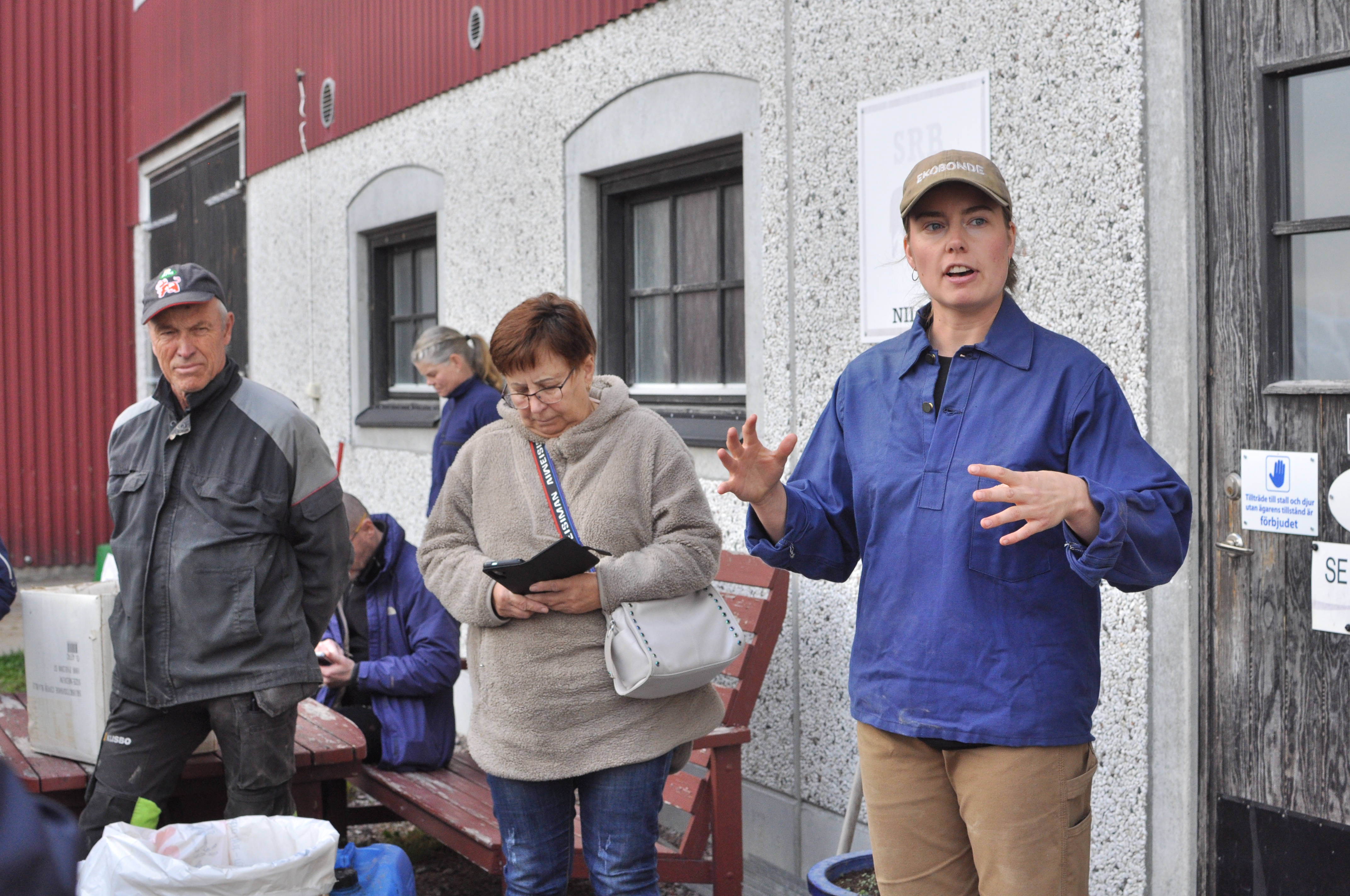 Kvinna i keps med man i keps och en kvinna som antecknar.