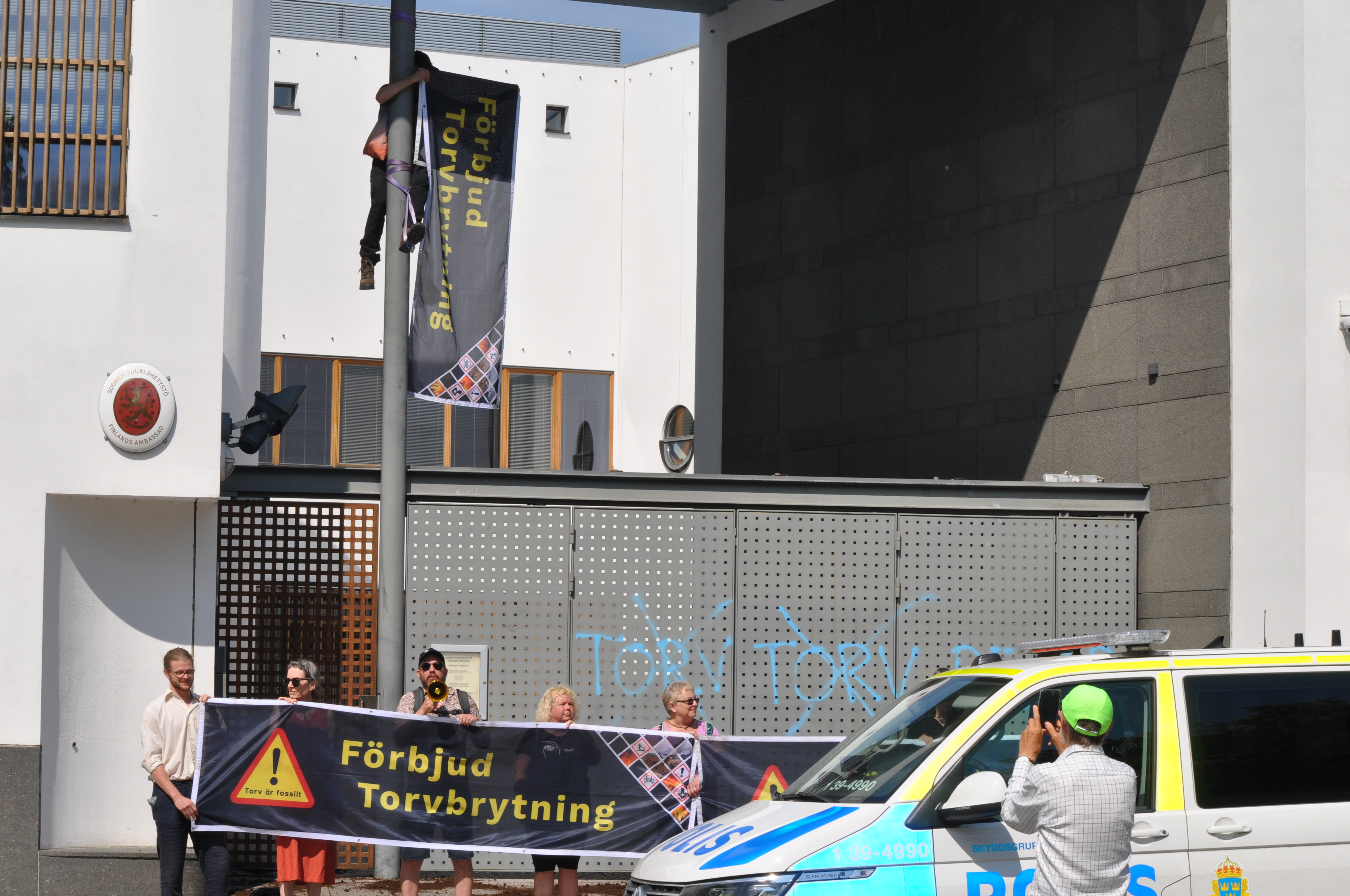 Demonstration med banderoller utanför byggnad.