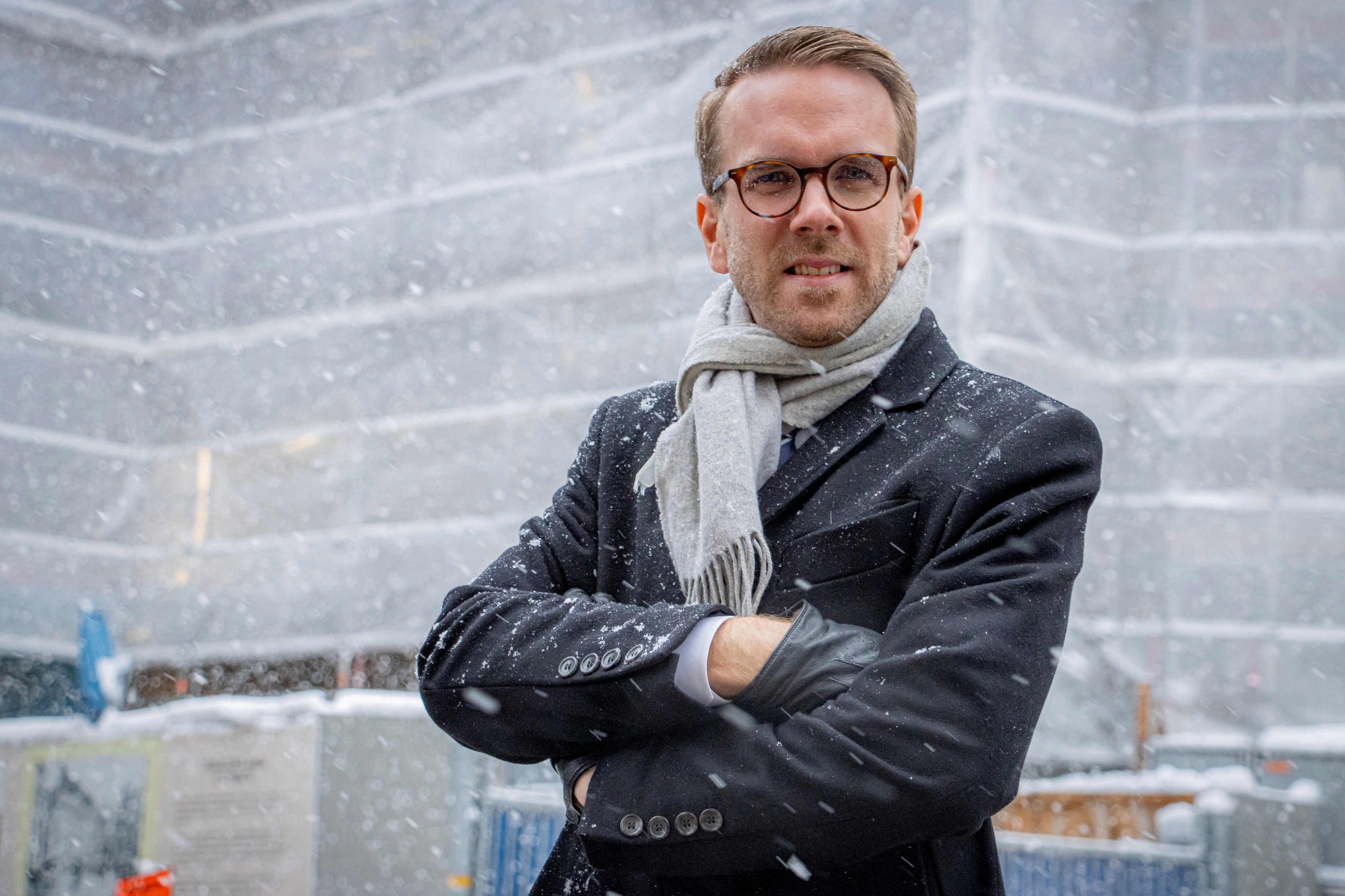 Man med glasögon och rock i snö