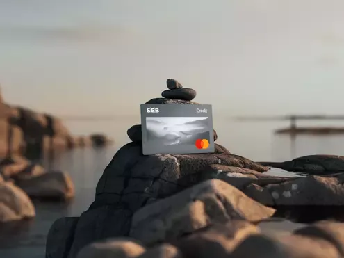 Ett SEB Mastercard-kreditkort på en sten vid vattnet.