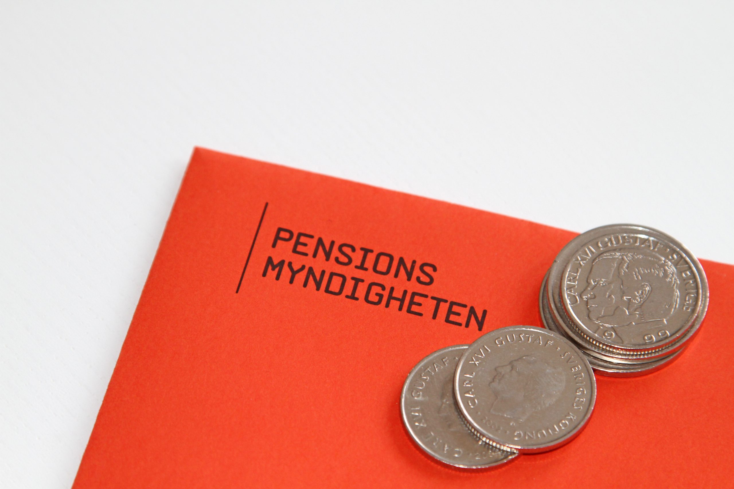 Ett orange kuvert från pensionsmyndigheten med några enkronor i hög ovanpå.