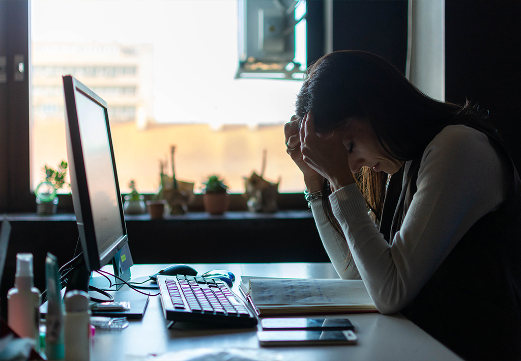 Utarbetad kvinna framför en dator