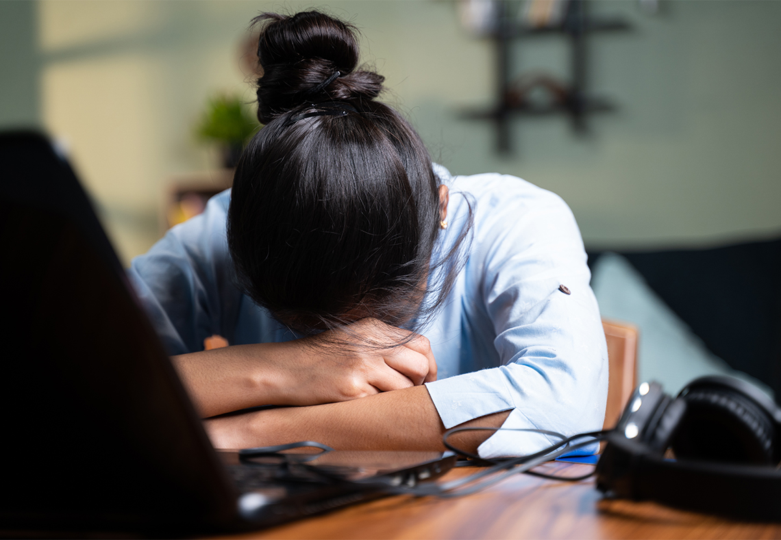 Utmattad kvinna framför dator.